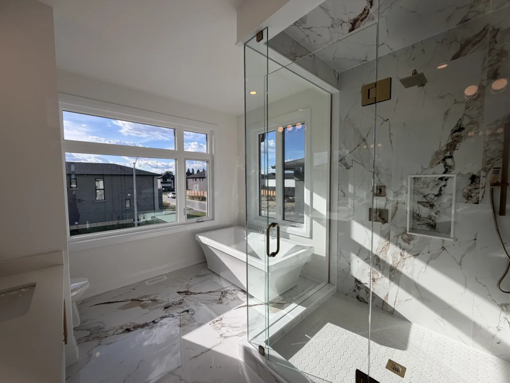 Bright primary ensuite with a frameless glass shower and marble-look porcelain tile