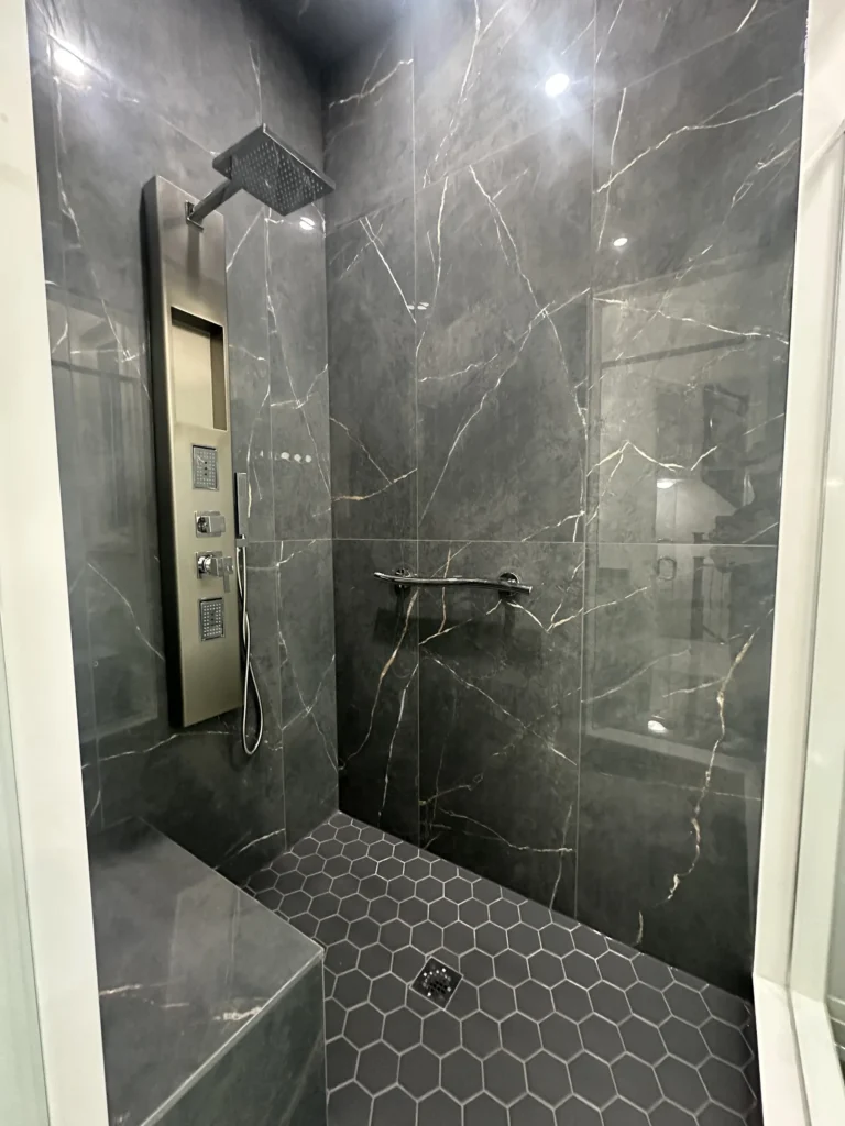 Dark marble-look shower with a hexagon tile floor and wall niche