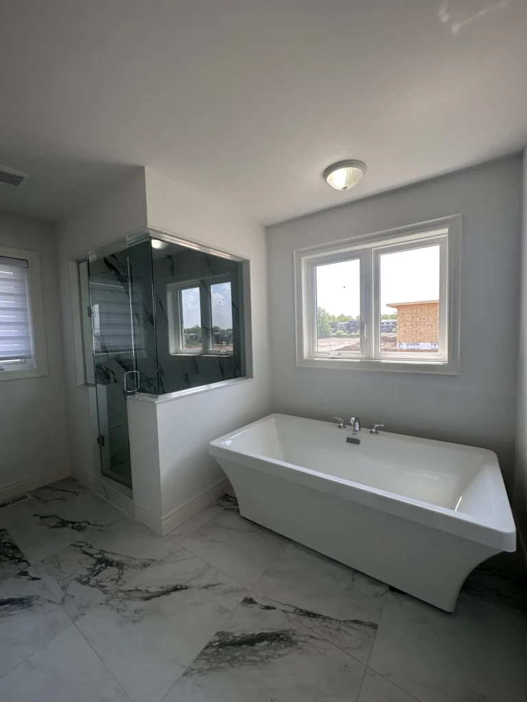 Ensuite with a freestanding tub, glass shower and marble-look floor