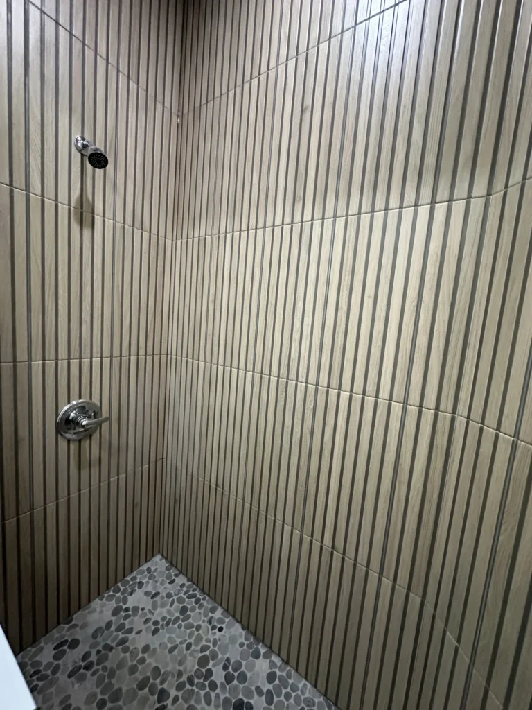 Shower with fluted wood-look wall tile and pebble floor