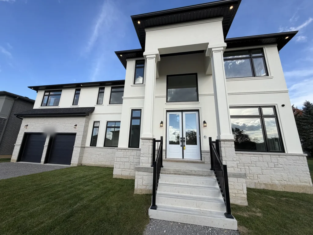 Front entry with tall columns and black railings on a modern two-storey home