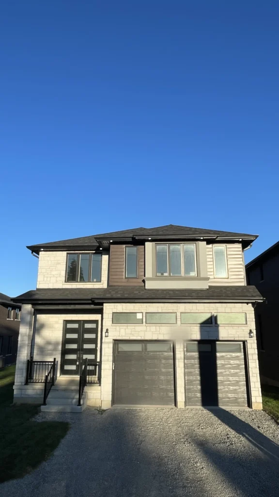 Two-storey new home exterior with stone, siding and a double garage in Hamilton