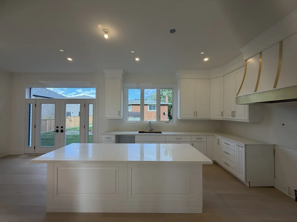Bright white kitchen with a large quartz island and French doors to the backyard