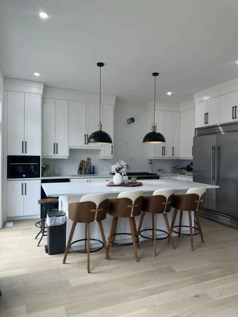 White kitchen with black pendant lights over an island with seating for five