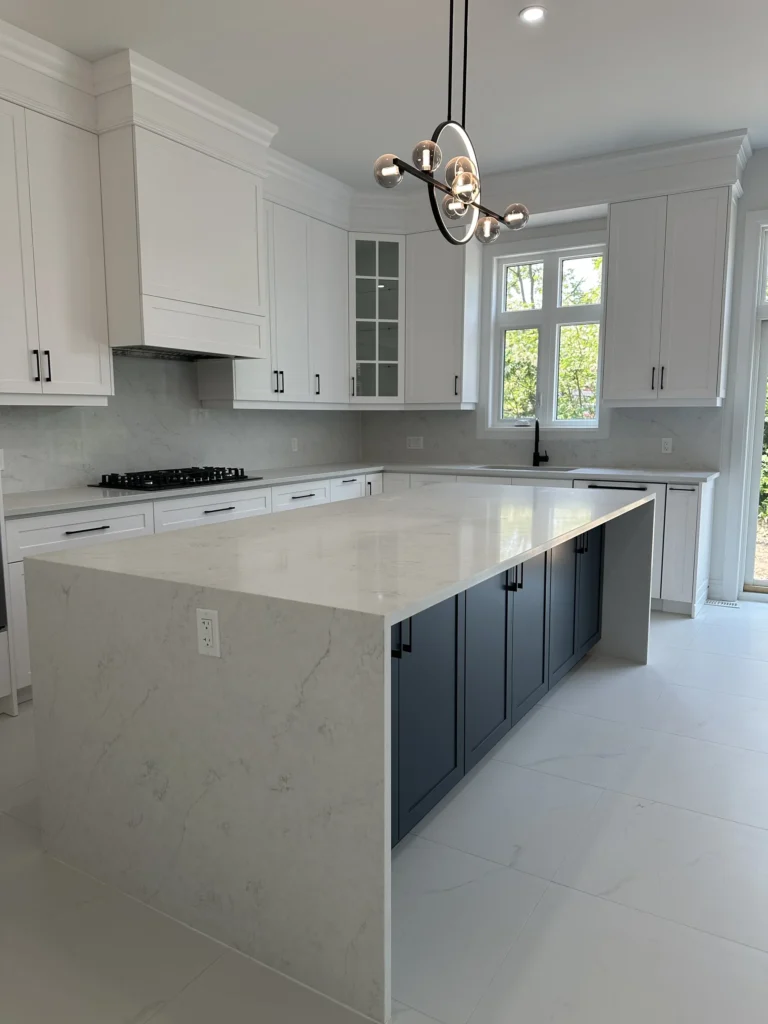 Navy waterfall island in a white kitchen with quartz countertops