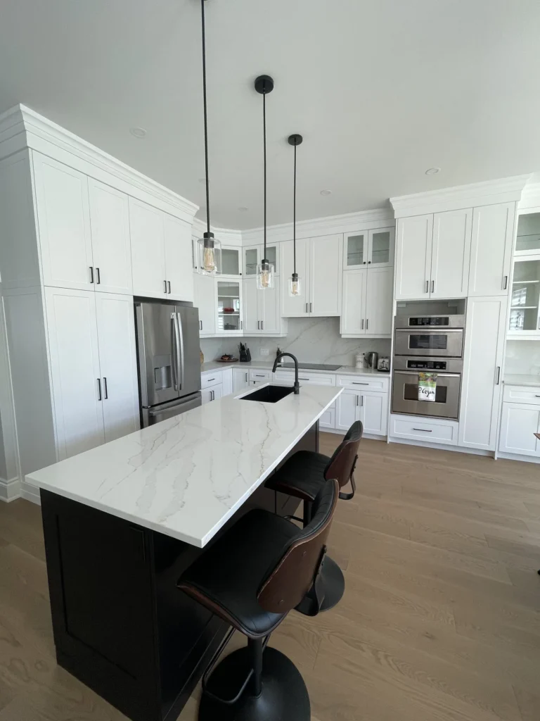 Navy island with white quartz top under pendant lights, with white cabinetry