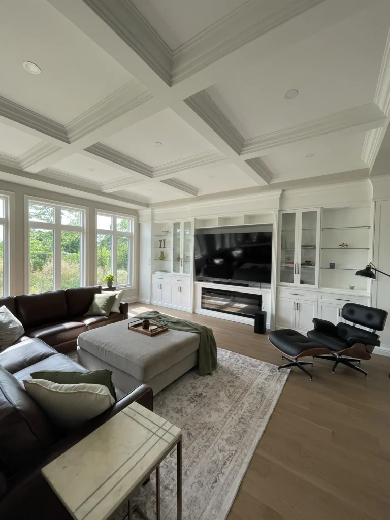 Furnished family room with a coffered ceiling and built-in wall unit with fireplace