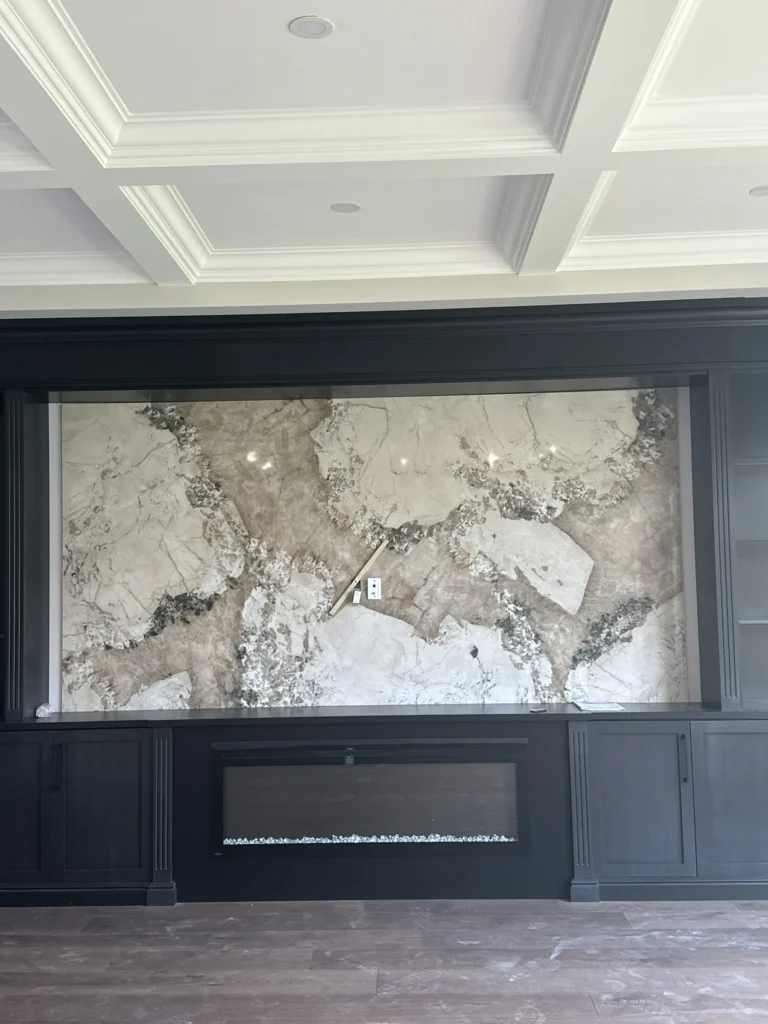 Fireplace wall clad in a large marble-look slab with dark built-ins