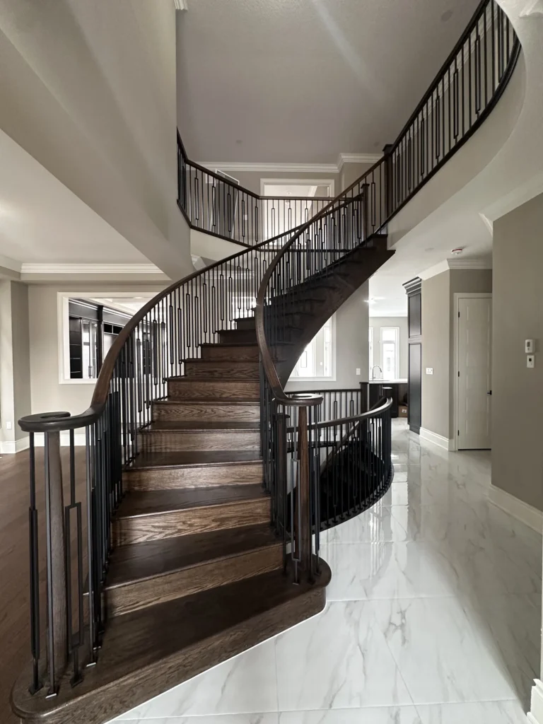 Curved staircase with dark stained treads and iron spindles